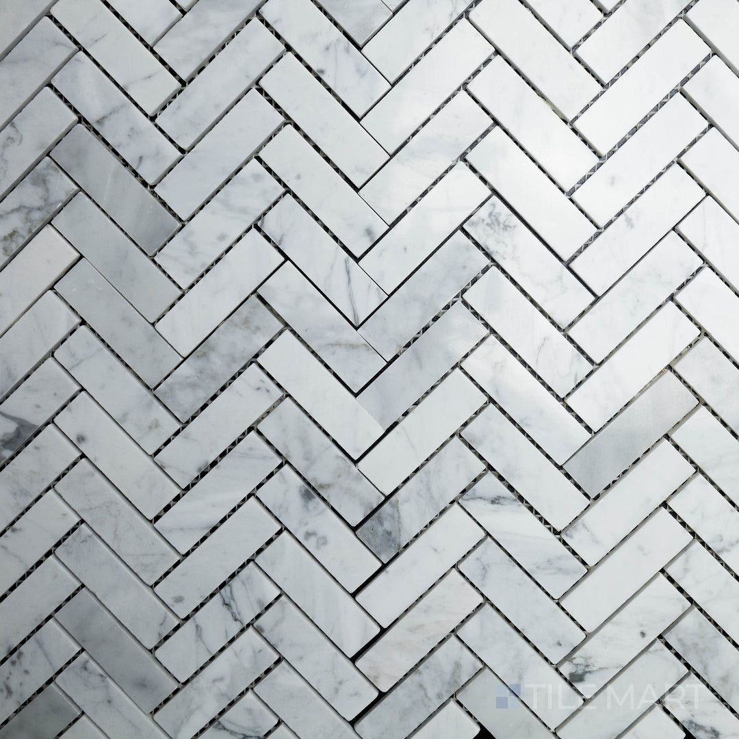 Captured from above, the Rockart Carrara Herringbone Polished Marble Mosaic features luxurious white Carrara marble with soft gray veining, arranged in a classic herringbone pattern.