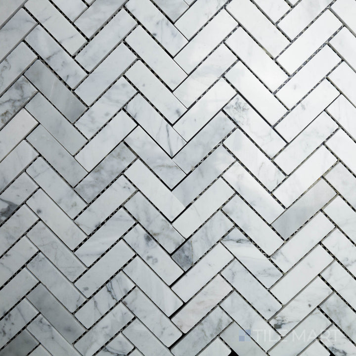 Captured from above, the Rockart Carrara Herringbone Polished Marble Mosaic features luxurious white Carrara marble with soft gray veining, arranged in a classic herringbone pattern.