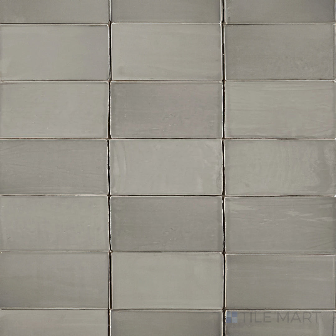 An overhead view of the St. Tropez Gris 2.5x5 inch bright ceramic tile showcases its smooth gray tone and glossy finish, adding a sleek and modern touch to any space.
