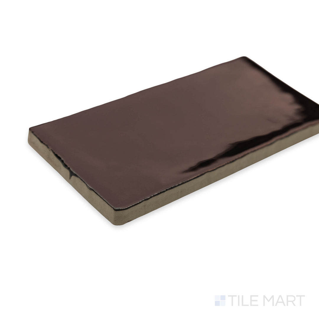 A rich and earthy corner perspective of St. Tropez Bronce 2.5x5 bright ceramic tile, showcasing its deep bronze shade and lustrous glaze.