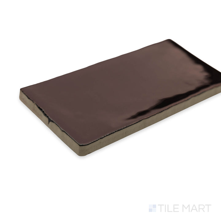 A rich and earthy corner perspective of St. Tropez Bronce 2.5x5 bright ceramic tile, showcasing its deep bronze shade and lustrous glaze.