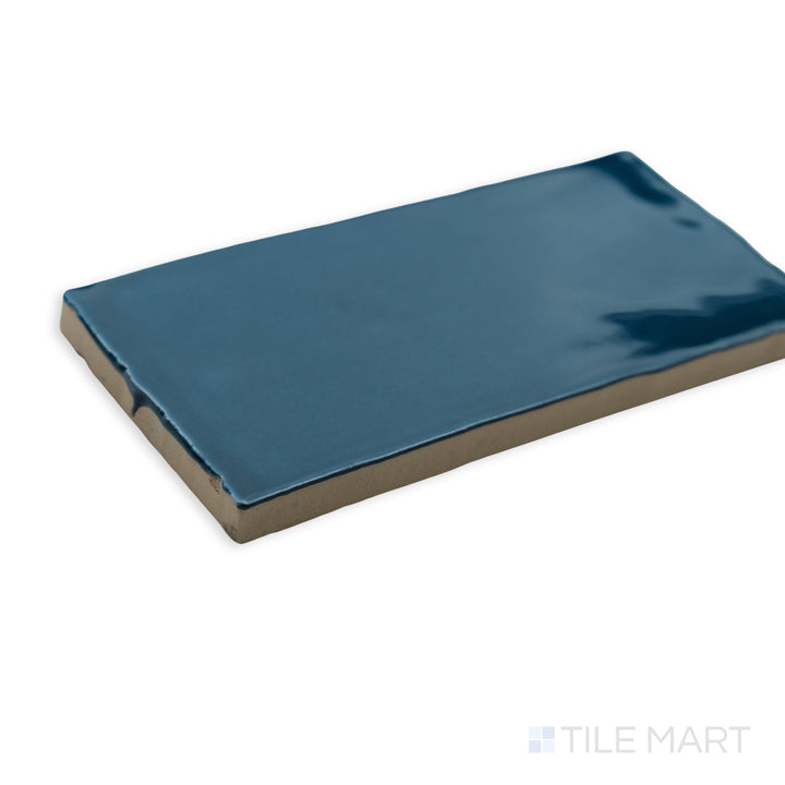 A bold and dynamic corner view of St. Tropez Azul 2.5x5 bright ceramic tile, featuring its striking blue color and reflective ceramic glaze.