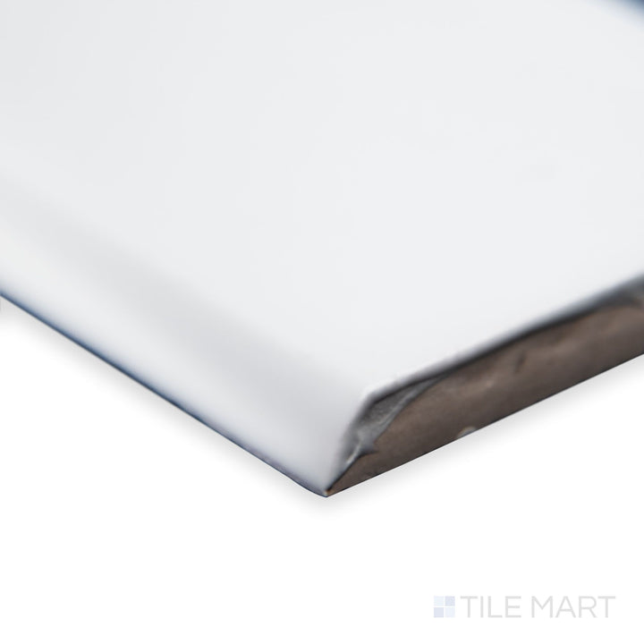A detailed corner view of St. Tropez Blanco 2.5x5 bright ceramic bullnose, highlighting its bright white tone, rounded edge, and reflective ceramic surface.