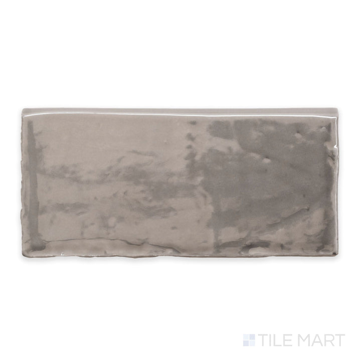 An overview of St. Tropez Gris 2.5x5 bright ceramic bullnose, featuring a soft grey hue with a glossy, reflective finish.