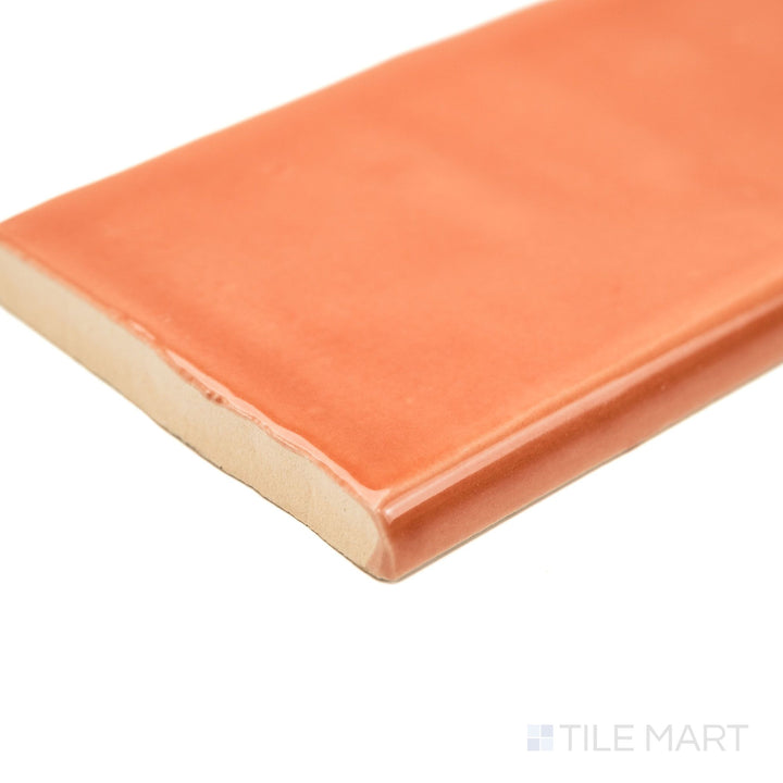 St. Tropez Coral 2.5x5 Bright ceramic bullnose tile in a corner view, showcasing its vibrant coral gloss and finished edge—ideal for colorful, refined borders.