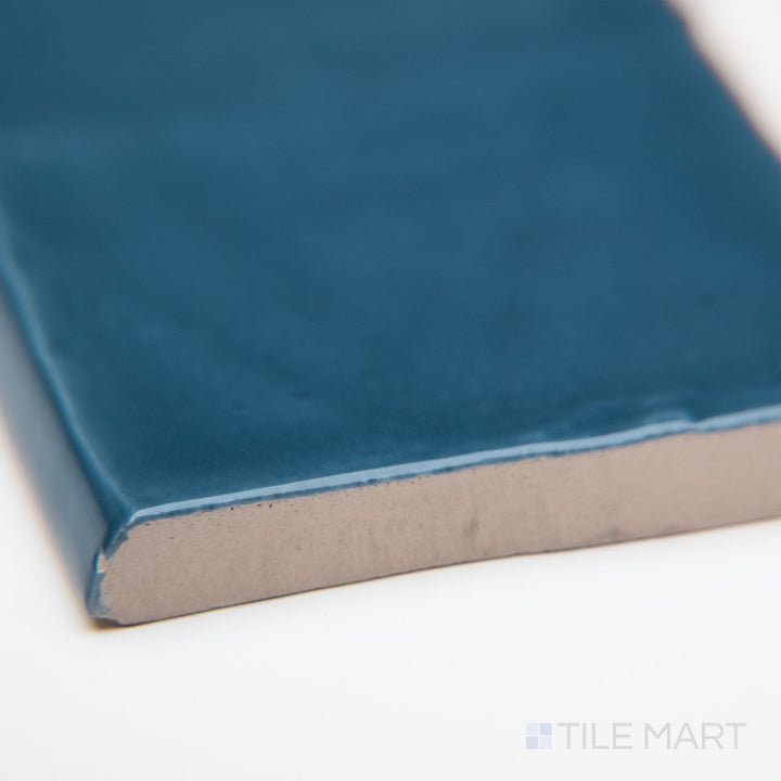 A detailed corner view of St. Tropez Azul 2.5x5 bright ceramic bullnose, showcasing its deep blue color, glossy ceramic glaze, and softly curved bullnose edge.