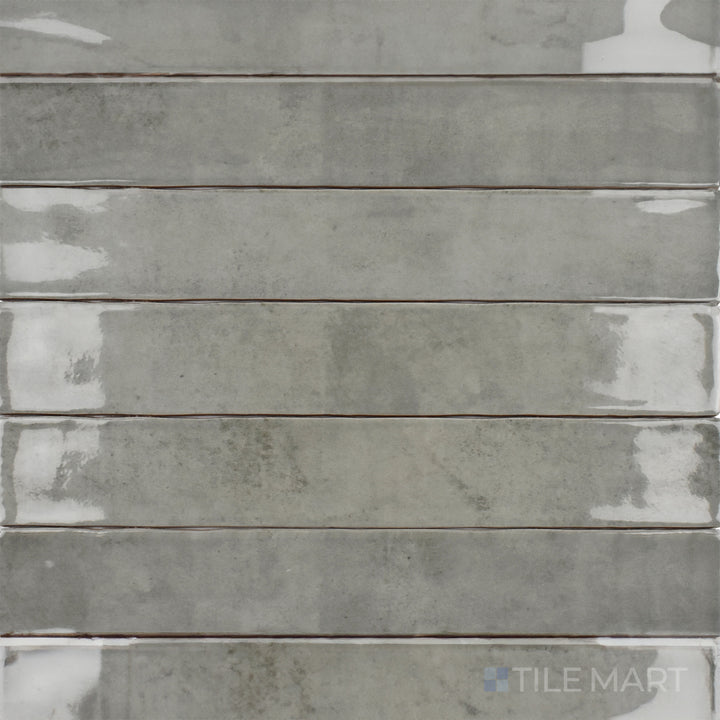 A top-down perspective of the Zellige Tender Gray 2x16 inch bright ceramic tile displays its soft gray tone with a high-gloss finish, offering a modern and elegant appeal.