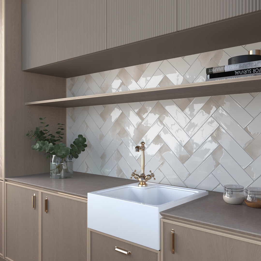 Light grey glossy tiles used as a kitchen backsplash with white cabinets.