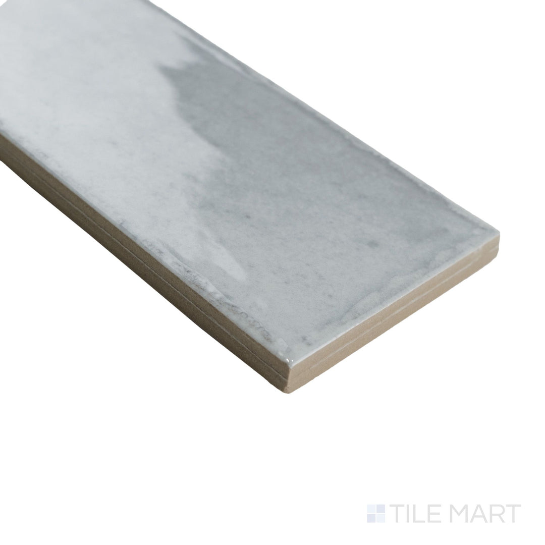 Angled corner view of Agadir Piedra 3x11 tile featuring neutral stone-inspired tones and a reflective finish along the edge.