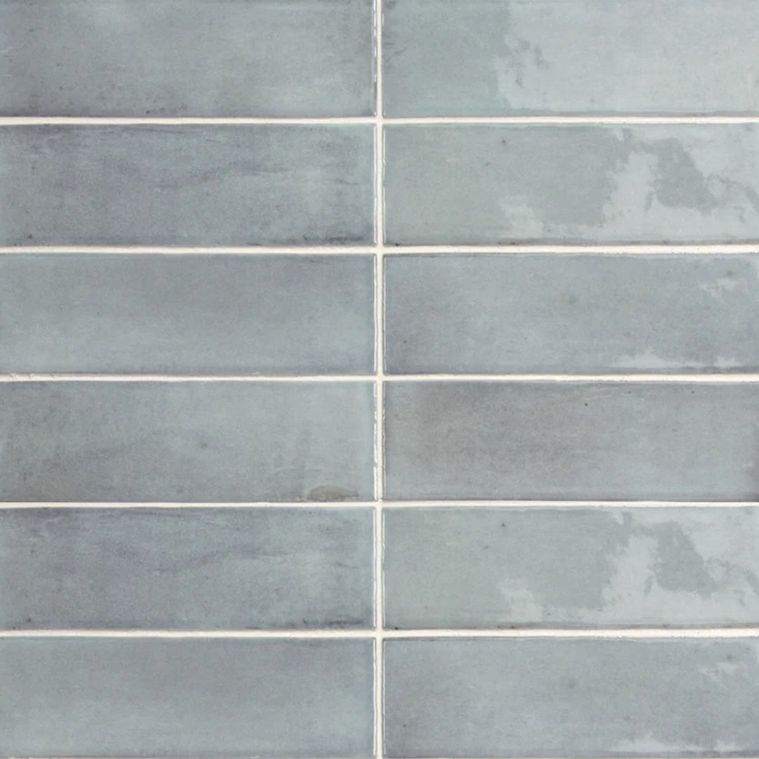 Top-down view of Soco Light Blue 2x6 inch glossy porcelain tile, showcasing a fresh pastel blue shade with a reflective, polished surface.