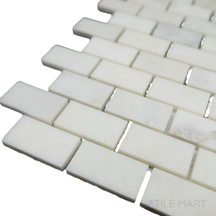 A softly lit corner shot enhances the natural beauty of Oriental White Marble 1x2 brick honed mosaic, emphasizing its smooth matte surface and traditional brick design.