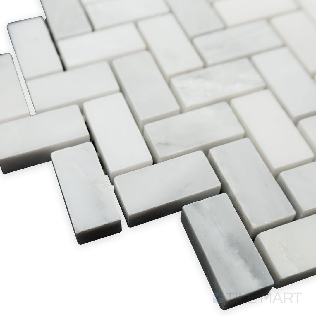 Captured from a dynamic corner angle, the Oriental White Marble 5/8x1-1/4 Herringbone honed mosaic reveals its precise layout and soft matte texture.