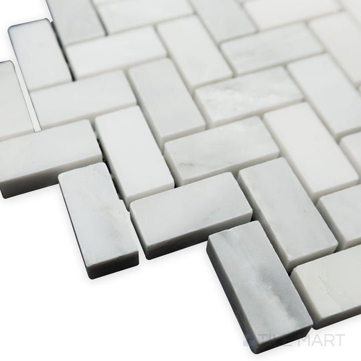 Captured from a dynamic corner angle, the Oriental White Marble 5/8x1-1/4 Herringbone honed mosaic reveals its precise layout and soft matte texture.