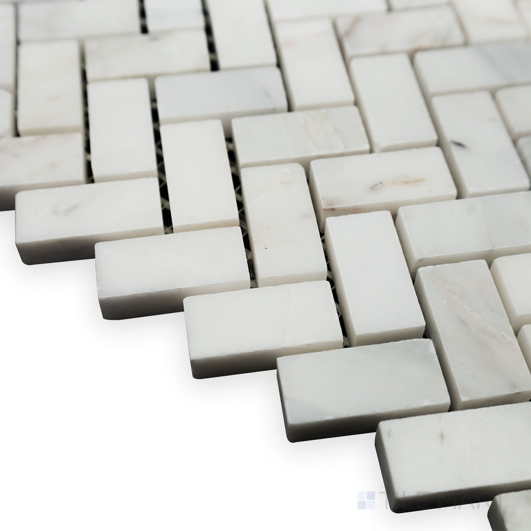 With light reflecting across its polished surface, this angled corner view of Oriental White Marble 5/8x1-1/4 Herringbone polished mosaic enhances its elegant design.