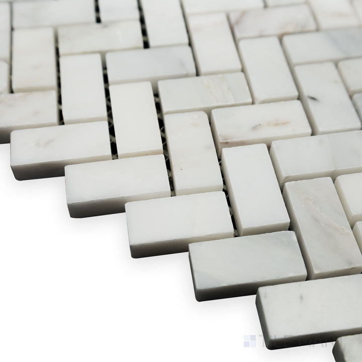 With light reflecting across its polished surface, this angled corner view of Oriental White Marble 5/8x1-1/4 Herringbone polished mosaic enhances its elegant design.