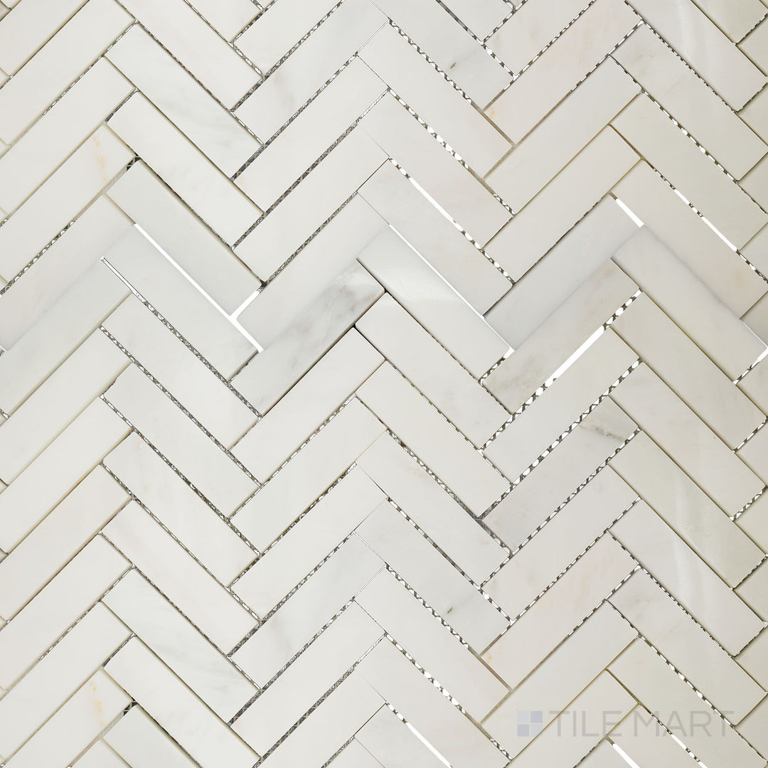 Overhead image of Oriental White Marble 1x4 herringbone polished mosaic, showcasing a glossy finish that enhances the natural veining of the stone.