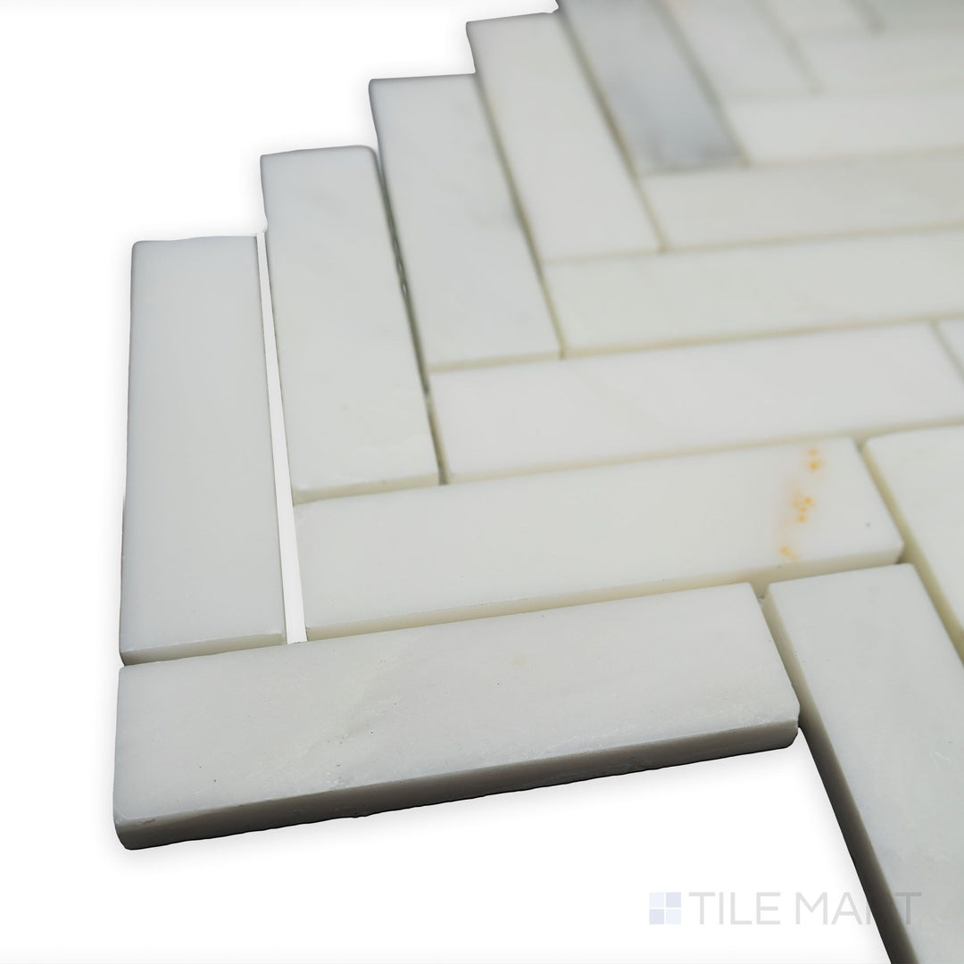 With a polished and structured aesthetic, this corner perspective of Oriental White Marble 1x4 Herringbone polished mosaic emphasizes its smooth, refined edges.