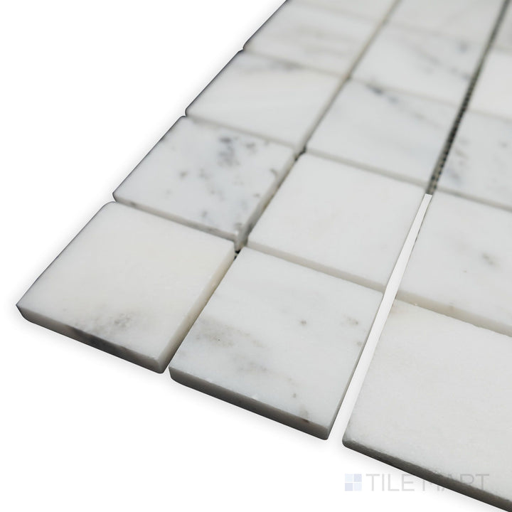 A spacious and structured pattern emerges in this close-up corner view of Oriental White Marble 2" Square honed mosaic, where its matte surface enhances its natural beauty.