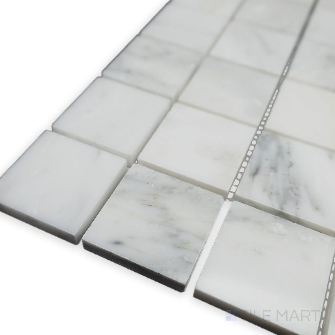 A luminous and polished surface elevates the refined grid pattern in this corner shot of Oriental White Marble 2" Square polished mosaic, creating a bright and sophisticated look.