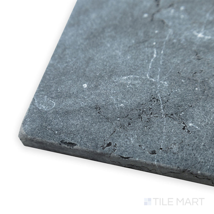 A rugged, textured appeal stands out in this corner shot of Negro Marquina Marble 12x12 tumbled tile, where softened edges and a natural finish create timeless character.