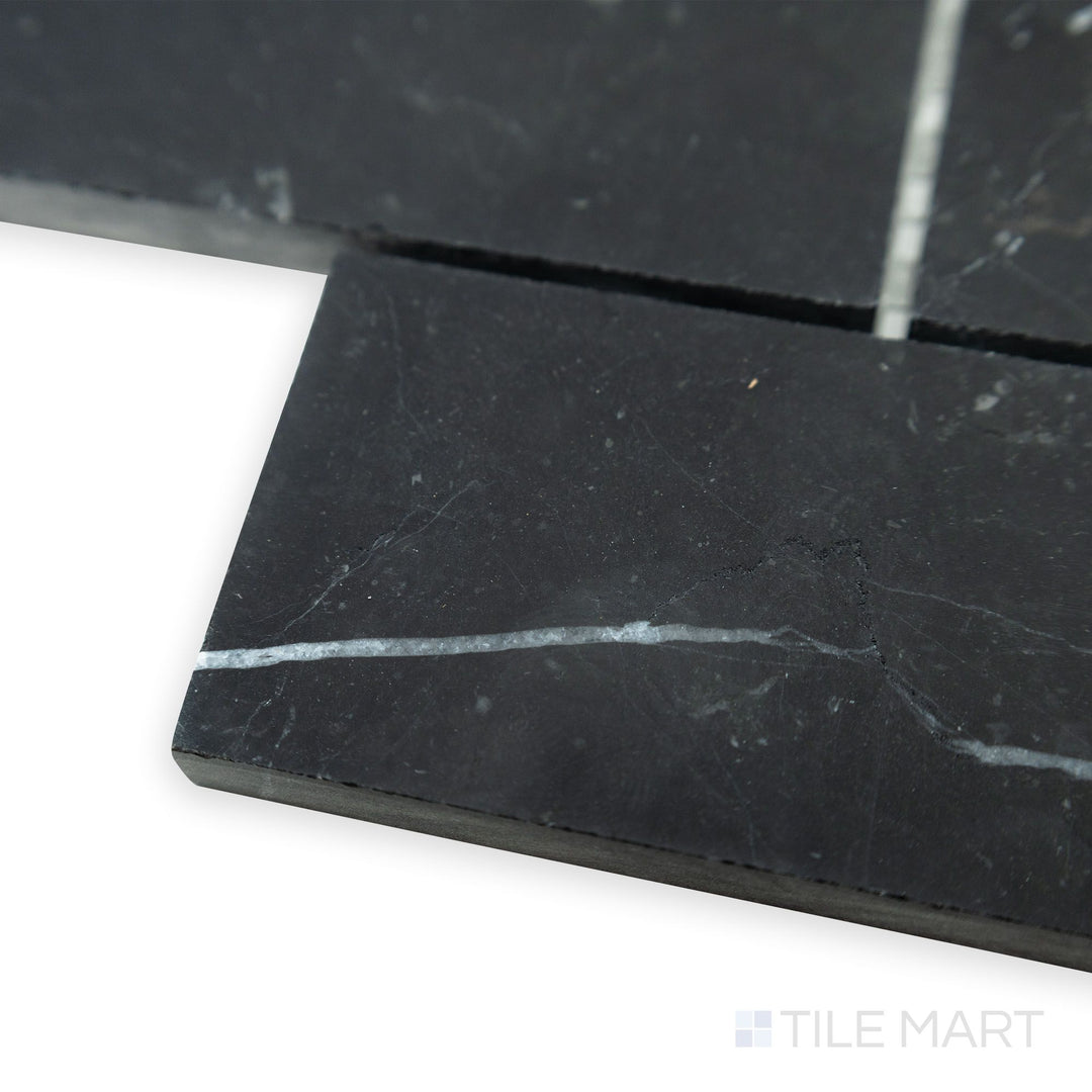 A bold and defined brick pattern emerges in this angled corner view of Negro Marquina Marble 2x4 brick honed mosaic, where its smooth matte finish refines the look.