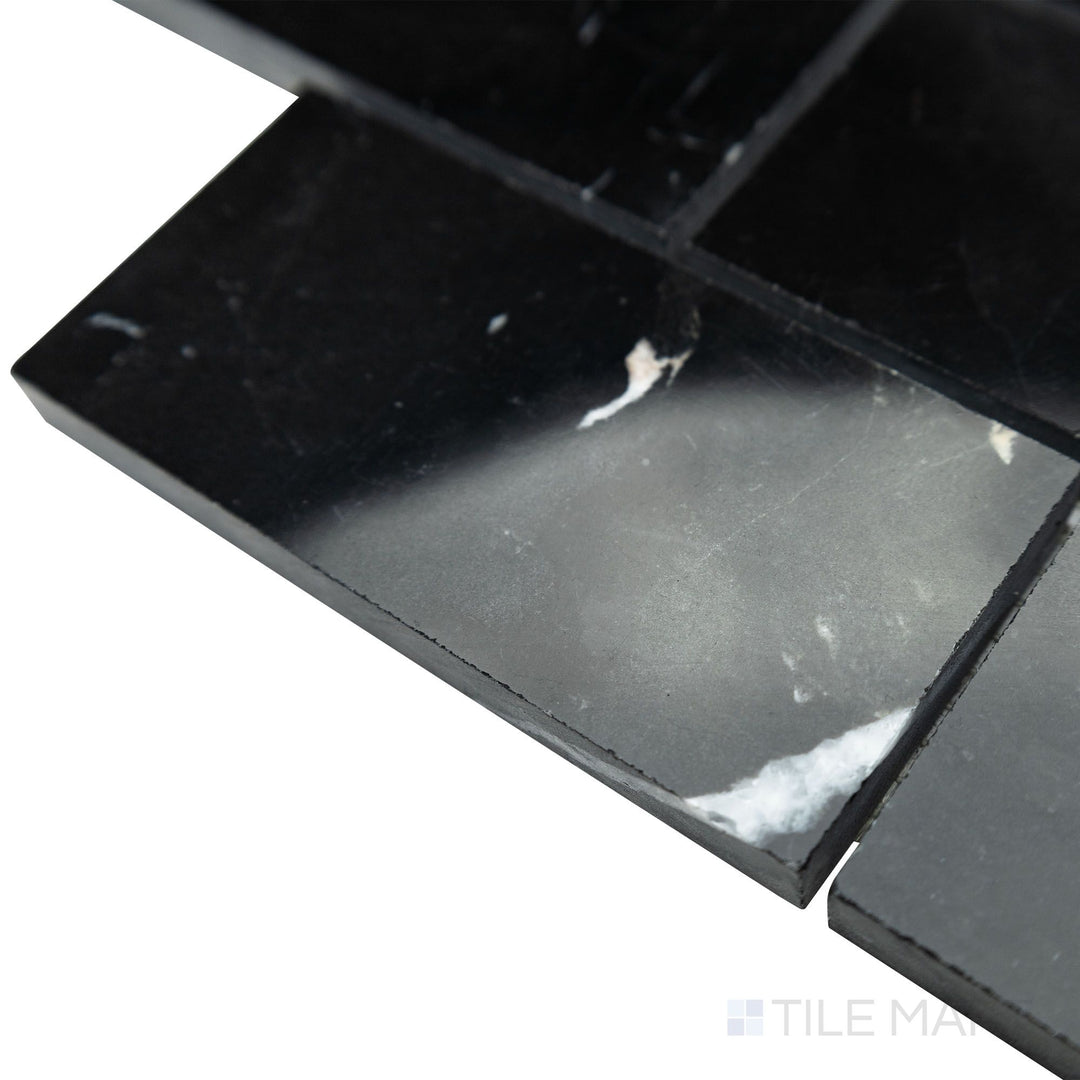 A polished brick layout comes into focus in this angled corner shot of Negro Marquina Marble 2x4 brick polished mosaic, where its glossy surface enhances the deep black tones.