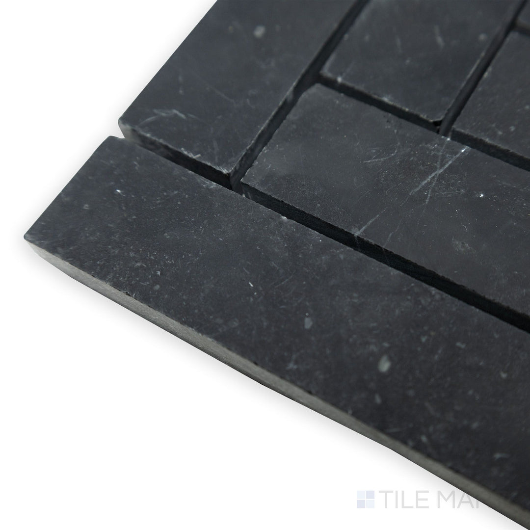 A seamless herringbone pattern extends in this angled corner shot of Negro Marquina Marble 1x4 herringbone honed mosaic, where the deep black marble meets a refined matte texture.