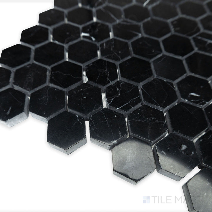 A polished hexagonal layout glows in this softly lit corner shot of Negro Marquina Marble 1" hexagon polished mosaic, enhancing the deep contrast of black marble with white veining.