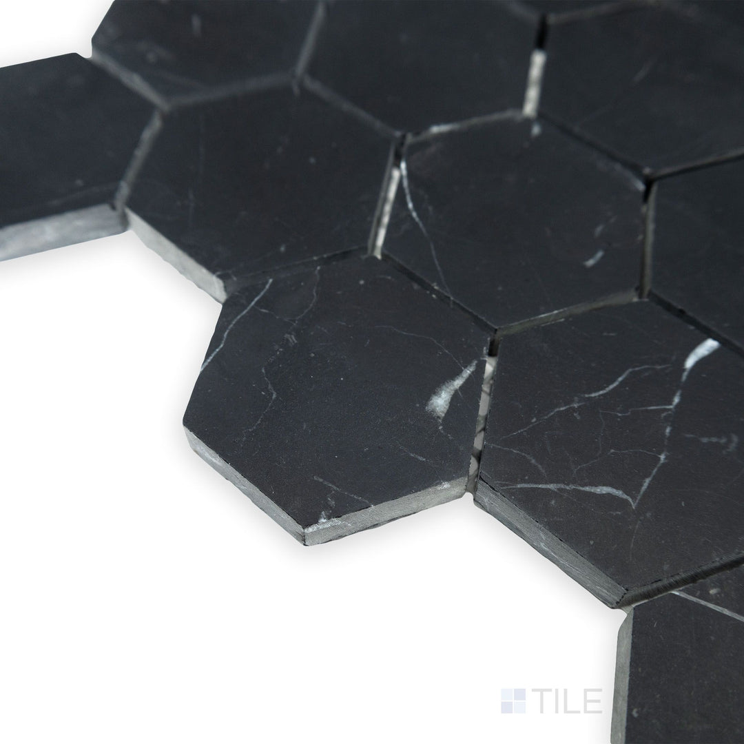 From an angled corner view, the structured geometry of Negro Marquina Marble 2" hexagon honed mosaic stands out, with its matte surface enhancing the deep black tones.