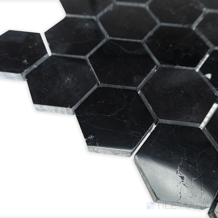 A polished hexagonal layout shines in this corner shot of Negro Marquina Marble 2" hexagon polished mosaic, where light reflects elegantly off its glossy surface.