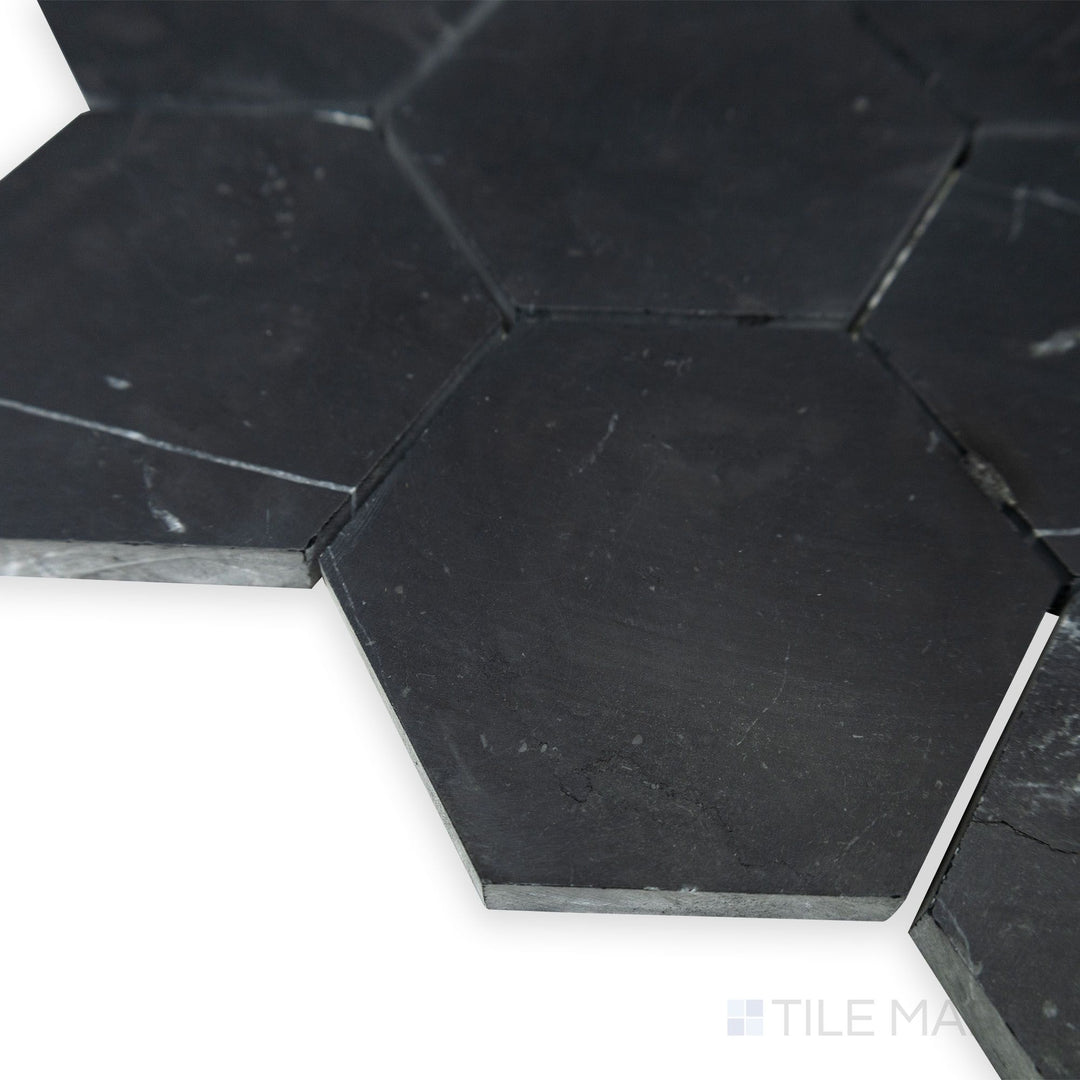 A refined hexagonal pattern emerges in this corner perspective of Negro Marquina Marble 3" hexagon honed mosaic, where the soft matte finish complements its bold geometric design.