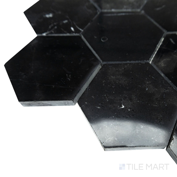 From a softly lit corner angle, the glossy surface of Negro Marquina Marble 3" hexagon polished mosaic enhances the rich contrast between its dark background and white veining.