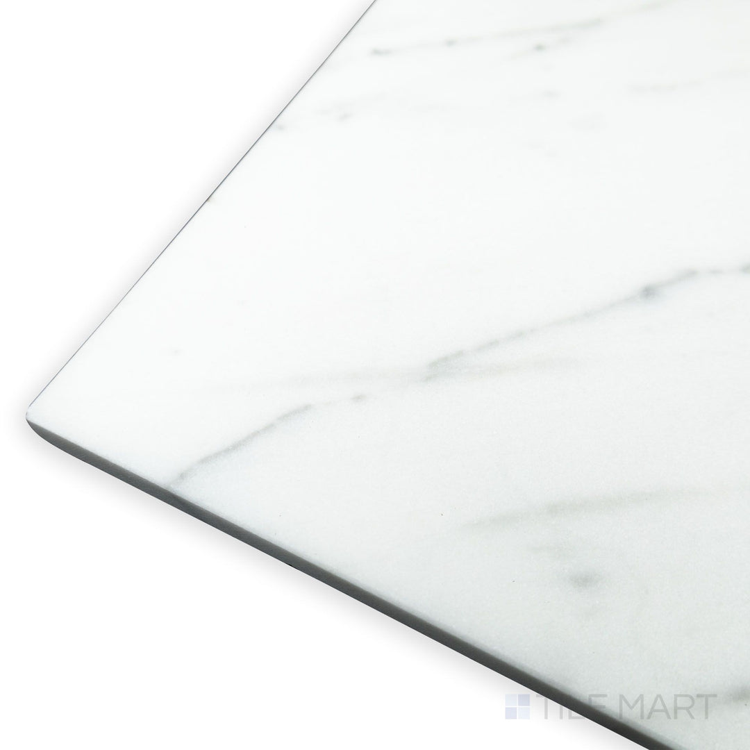 A soft corner angle highlights the expansive format of Statuary White Marble 12x24 honed tile, where its natural veining flows elegantly across the surface.
