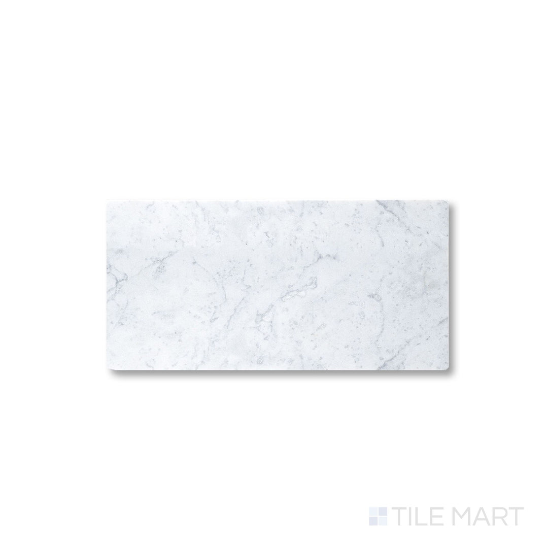 Close view of tumbled White Carrara marble 3x6 tile with softened edges and natural stone texture