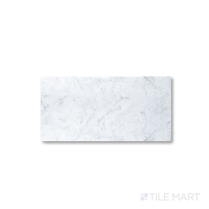 Close view of tumbled White Carrara marble 3x6 tile with softened edges and natural stone texture