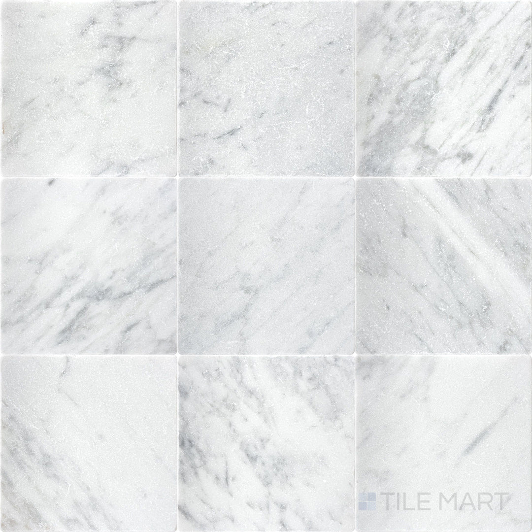 Top-down view of White Carrara Marble 4x4 tumbled tile featuring a textured, rustic marble surface with softened edges for organic wall or floor designs