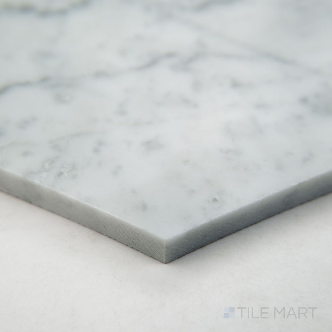 Angled corner shot of White Carrara Marble 6" hexagon honed tile featuring smooth matte texture and elegant white and gray marble veining