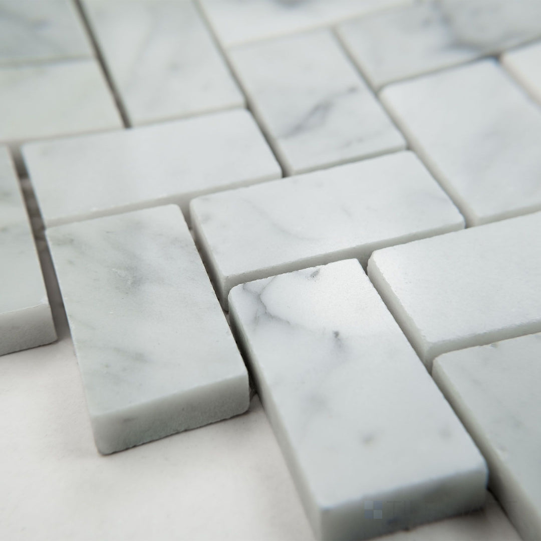Tile shown from corner angle of White Carrara Marble basketweave with black dot honed mosaic highlighting woven matte marble and dark accents