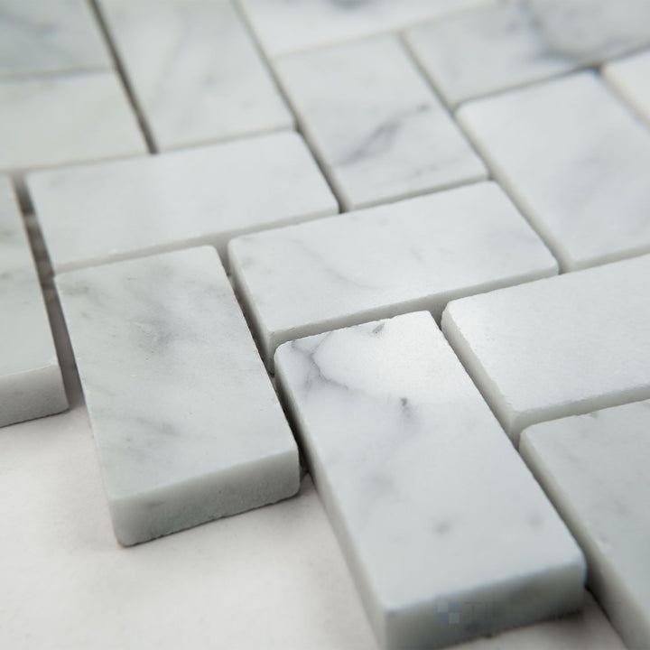 Tile shown from corner angle of White Carrara Marble basketweave with black dot honed mosaic highlighting woven matte marble and dark accents