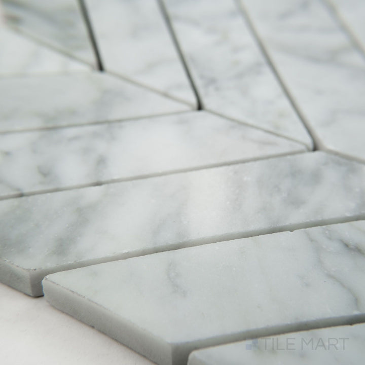 Tile corner display of White Carrara Marble 1x4 chevron honed mosaic showing matte marble tiles forming a striking chevron layout