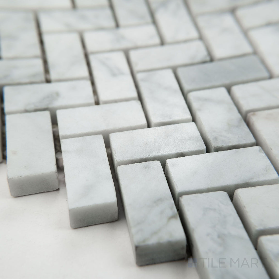 Tile corner display of White Carrara Marble 5/8x1-1/4 herringbone polished mosaic highlighting shiny marble tiles in a dynamic V pattern