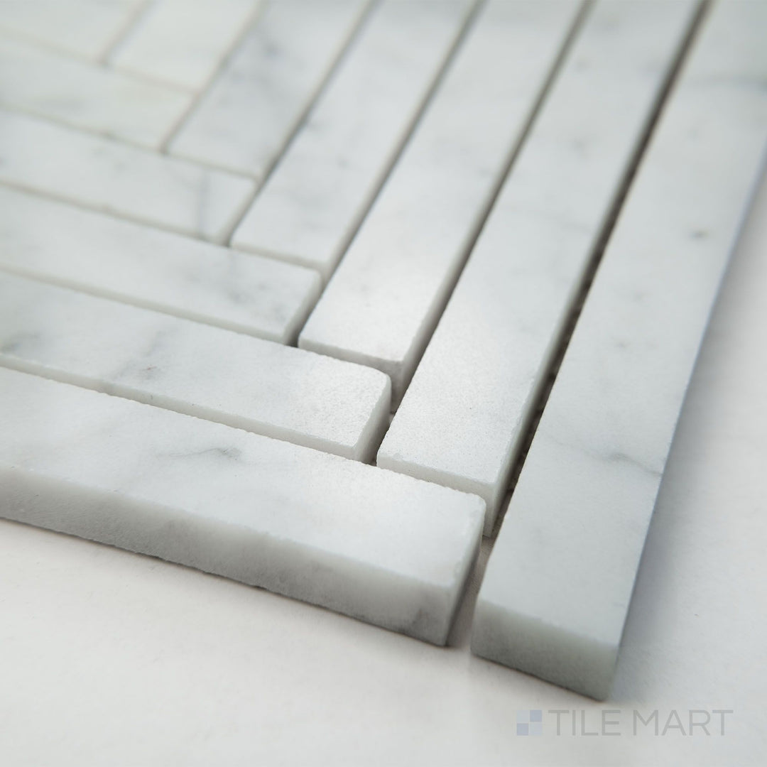 Angled view of White Carrara Marble 5/8x6 herringbone polished mosaic showing glossy marble arranged in a classic V-shaped herringbone