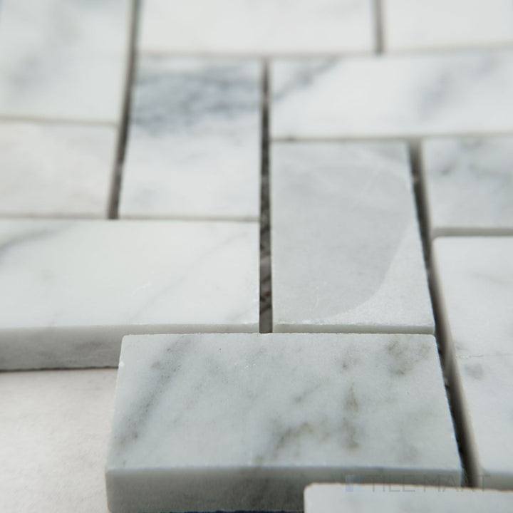 Tile corner display of White Carrara Marble 1x2 herringbone honed mosaic highlighting rectangular matte marble tiles in a herringbone pattern