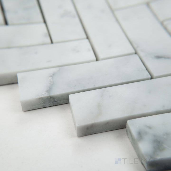Angled view of White Carrara Marble 1x3 herringbone honed mosaic highlighting matte marble rectangles arranged in a clean zigzag pattern