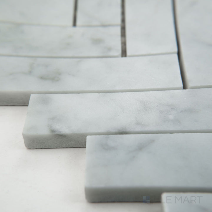Tile shown from corner angle of White Carrara Marble 1x4 herringbone honed mosaic featuring long matte marble pieces in a tight herringbone design