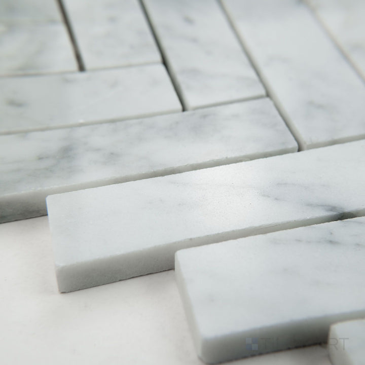 Corner view of White Carrara Marble 1x4 herringbone polished mosaic showcasing polished marble rectangles arranged in a stylish herringbone pattern