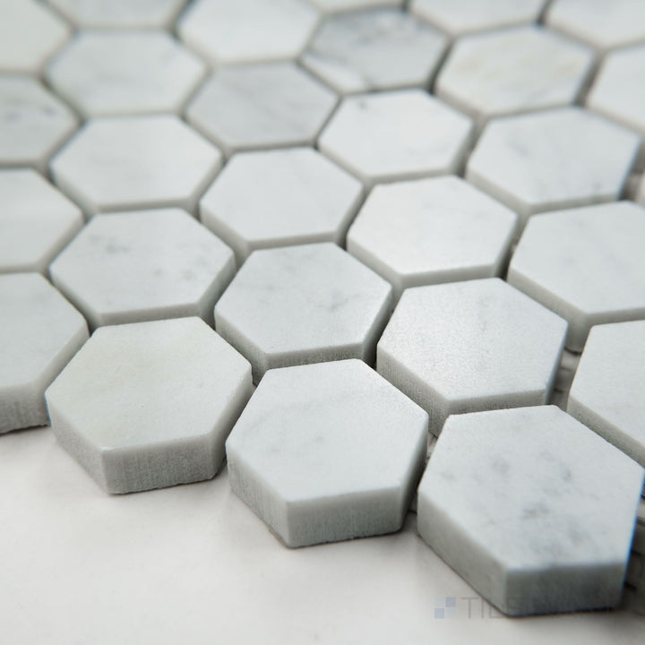 Tile shown from corner angle of White Carrara Marble 1" hexagon polished mosaic featuring glossy marble hexagons arranged neatly