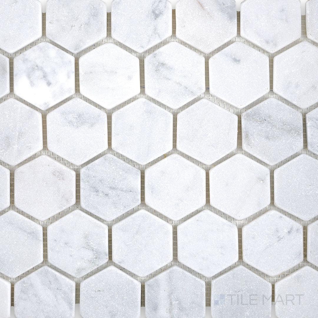 Top-down perspective of White Carrara Marble 2-inch hexagon tumbled mosaic with lightly textured edges for a rustic and timeless natural stone look