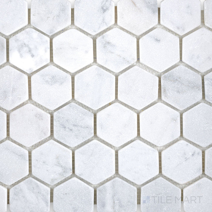 Top-down perspective of White Carrara Marble 2-inch hexagon tumbled mosaic with lightly textured edges for a rustic and timeless natural stone look