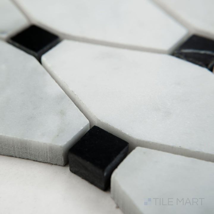 Tile shown from corner angle of White Carrara Marble elongated octagon with black honed mosaic displaying a soft matte finish with bold black details